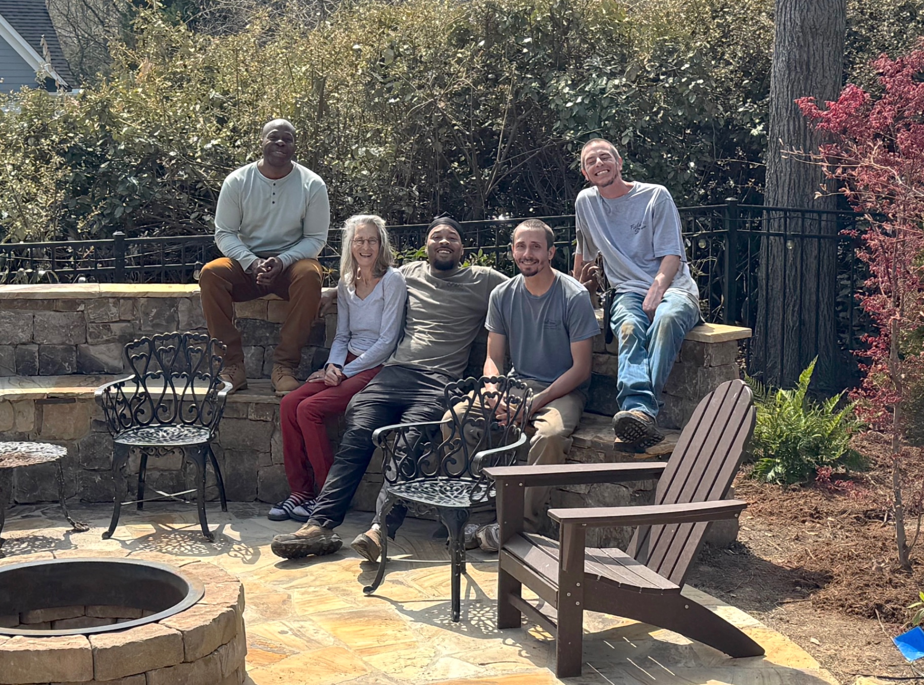 The Land Stewards team gathered on a stone seat wall in a finished garden